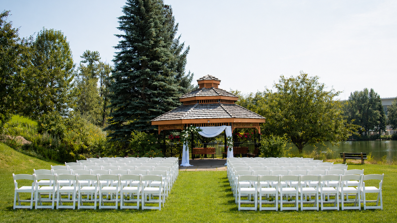 Sunlit outdoor wedding ceremony setup on the Belvedere Lawn at Waterfront Park, featuring pristine rows of white chairs facing an elegant gazebo set against sweeping lakeside parkland.